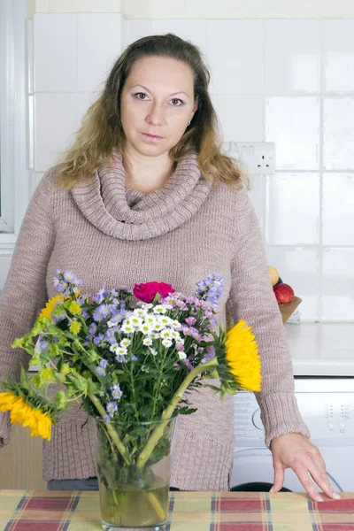 Portrait of positive housewife with flowers — Stock Photo, Image