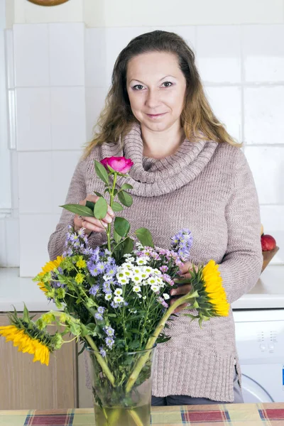 Portrét pozitivní hospodyně s květinami — Stock fotografie