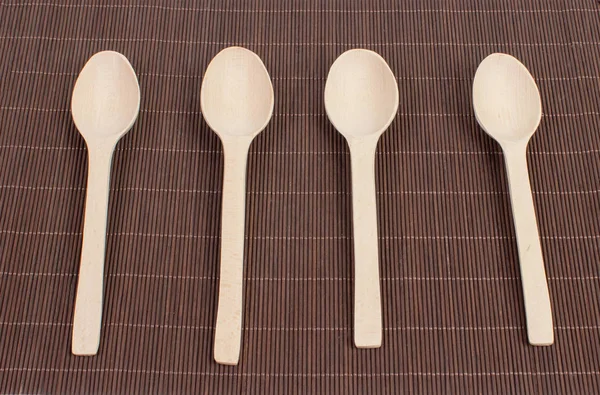 Wooden spoons on a dark bamboo canvas — Stock Photo, Image