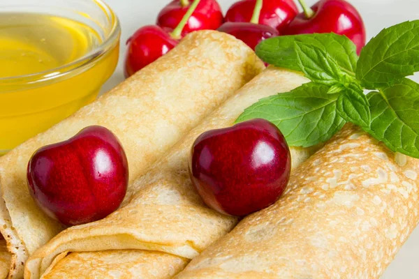Homemade dessert. Fried pancakes with honey. Crepe with cherry on white plate background. — Stock Photo, Image