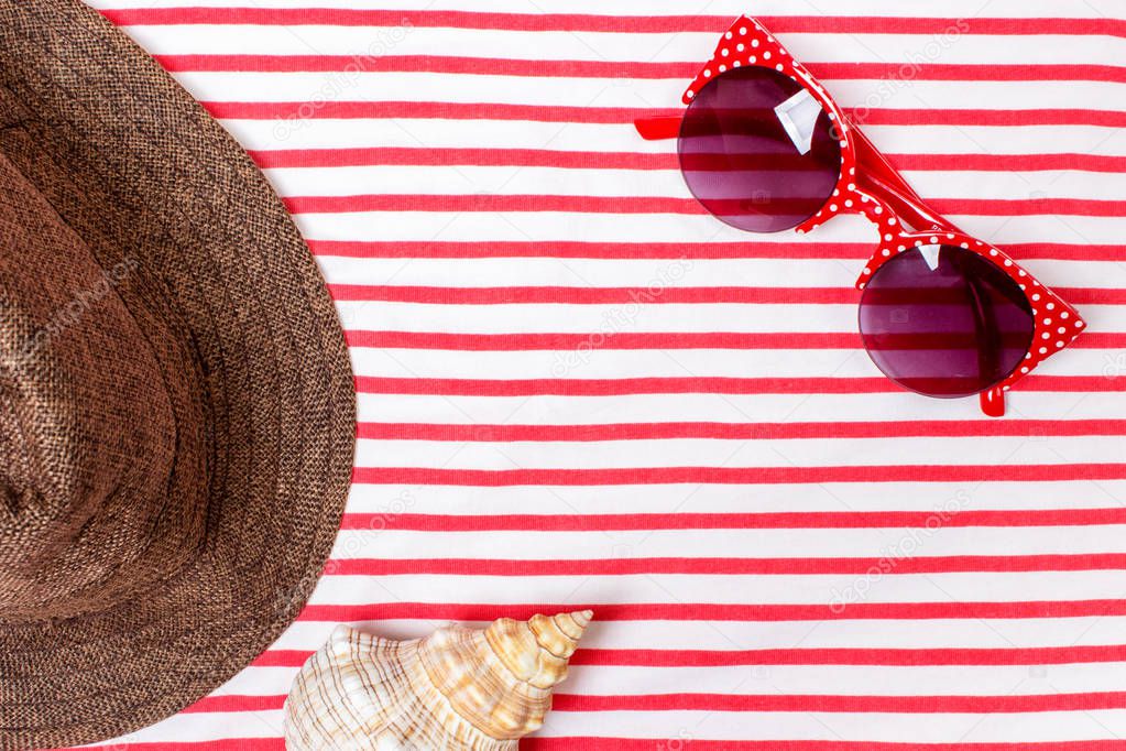 Summer vacation, tourism, travel, holiday concept. Sea shells, beach hat and striped blanket in white. Top view with space for text.