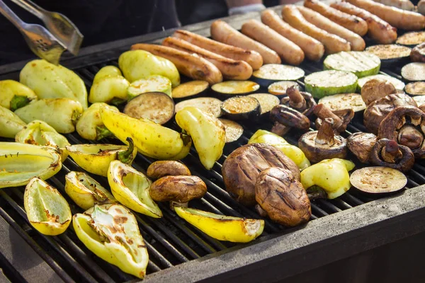 Verschiedene leckere Grillgerichte mit Gemüse über dem Grill auf der Holzkohle. Wurst, Steak, Paprika, Pilze, Zucchini. — Stockfoto
