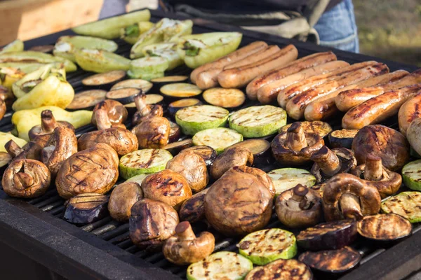 Verschiedene leckere Grillgerichte mit Gemüse über dem Grill auf der Holzkohle. Wurst, Steak, Paprika, Pilze, Zucchini. — Stockfoto