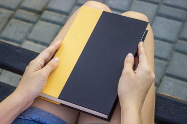 Parkta bir kitap tutan genç bir kadın.