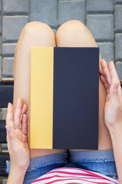 Parkta bir kitap tutan genç bir kadın.