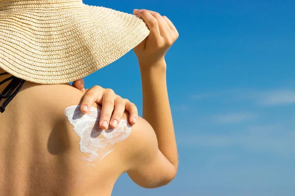 Sonnencreme Sonnencreme. Frau mit Hut trägt Sonnencreme auf der Schulter im Freien bei Sonnenschein an einem schönen Sommertag. — Stockfoto