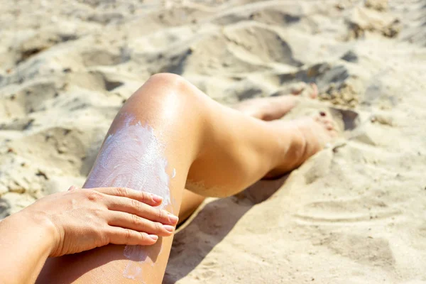 Hermosa hembra joven, aplicando crema bronceadora en la playa . — Foto de Stock