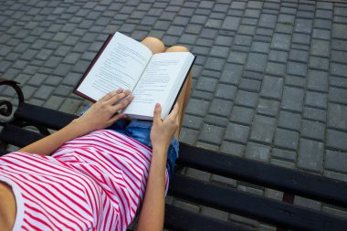 Kız bir bankta oturan ve bir kitap okuma. Bir genç kızın bir kitap okuma Üstten Görünüm.