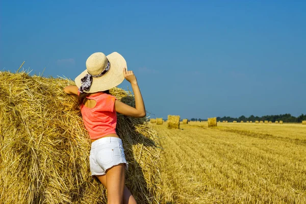 Mladá bruneta venkovská dívka v klobouku poblíž stohy — Stock fotografie