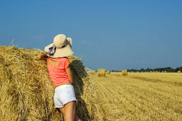 Kız bir saman balya duran ve alanında mesafe bakarak