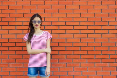 tuğla duvarın üzerinden açık poz çarpıcı genç kadın.