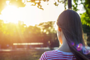Uzun kahverengi saçlı'nde Günbatımı gönüllülük a kitap parkta güzel bir kızla arkadan görünüm