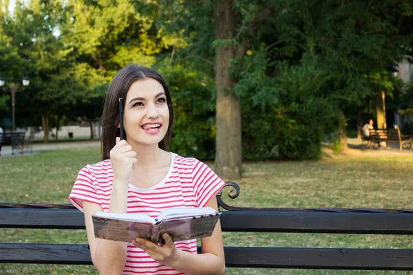 Kafasını Park tarafından bir kitap ve bir kalem ile tezgah düşünme kız çarpıcı