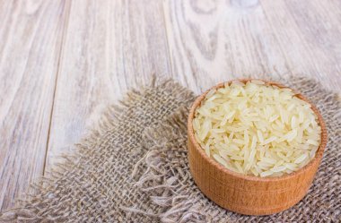 Ahşap masa üzerinde kase ve çuval çuval pirinç yasemin