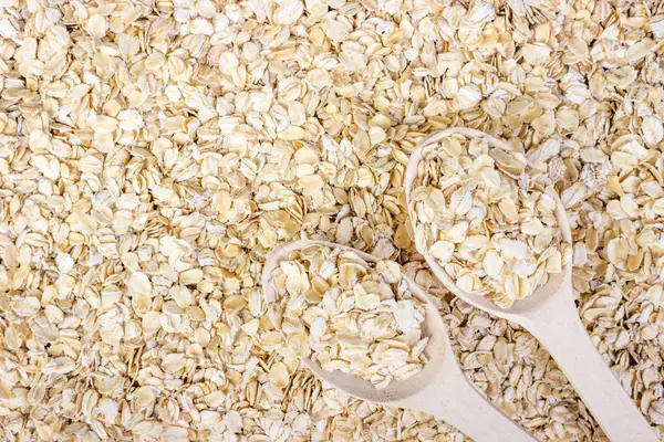 pile of oat flakes and wooden spoon on oat flakes background