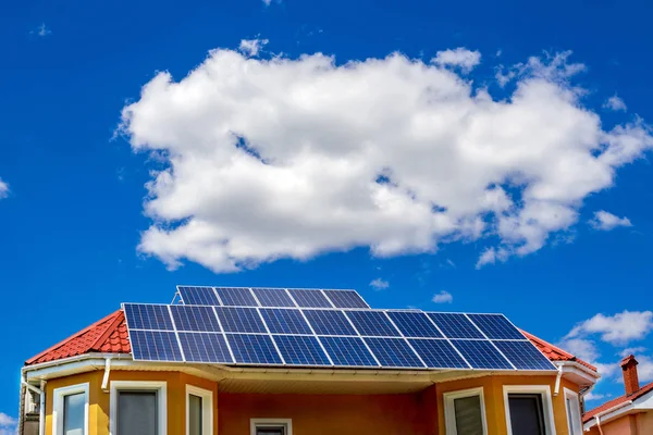 Panneau solaire sur un toit rouge reflétant le soleil et le ciel bleu — Photo