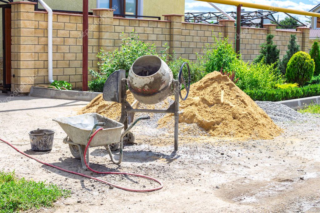 Cement mixer machine at construction site, tools and sand