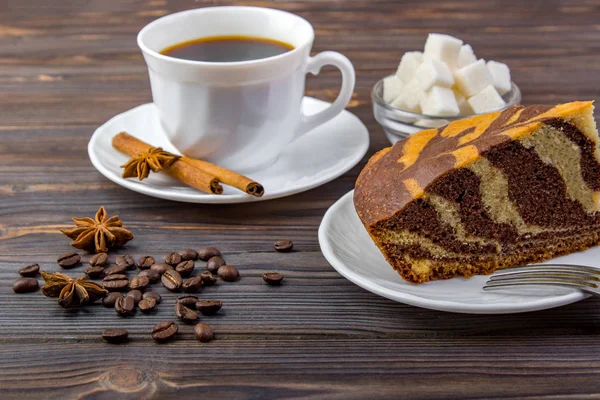 Um pedaço de bolo com uma xícara de café. Varas de canela, anis, garfo e uma tigela com cubos de açúcar no fundo de madeira escura — Fotografia de Stock