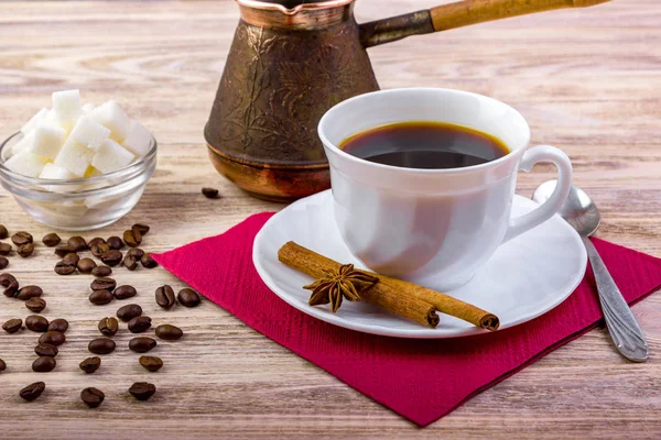 白杯碟，黑色热咖啡配咖啡豆，一碗茶勺、 茴香、 肉桂棒木制带纹理的背景上的白色糖多维数据集 — 图库照片