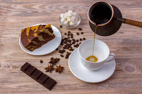 Вид сверху на чашку кофе и кусок вкусного торта на блюдце, кофейную фасоль, миску с сахарными кубиками, шоколадный батончик и анис на ярком деревянном столе — стоковое фото