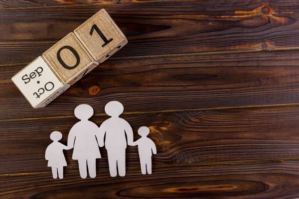 Pappfigurer i familjen på ett träbord med 1 September i en dekorativ kalender. En symbol för enighet och lycka. Ovanför dotter bubblan, som du kan skriva in ditt meddelande. — Stockfoto