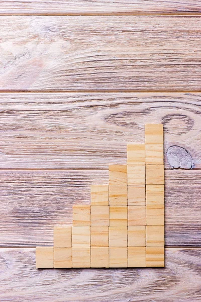 A wooden blocks cube over black wooden textured background with copy space for add word text title. Concept or conceptual Wood block stair or seven steps. Cubic.