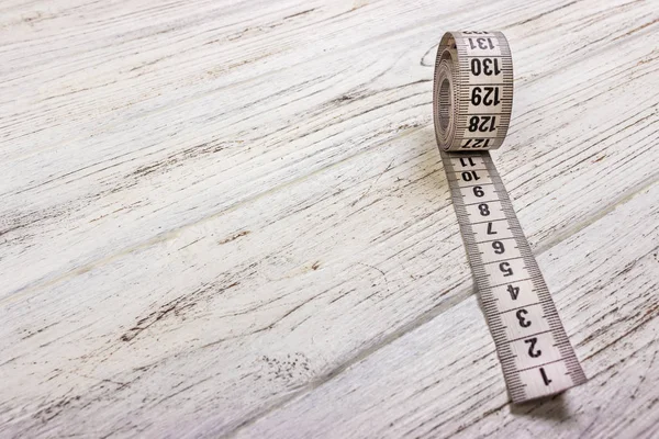 Fermer ruban à mesurer tailleur sur fond de table en bois. Ruban à mesurer blanc profondeur de champ faible . — Photo