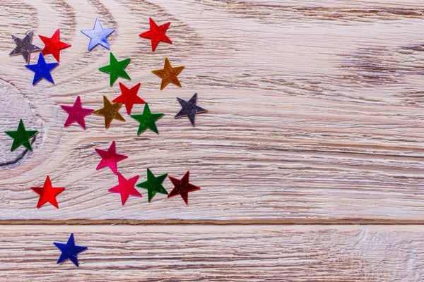 ahşap arka plan üzerinde renkli yıldız konfeti. Tatil