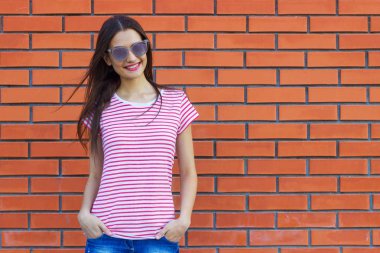 çekici genç kadın giyinmiş bir kırmızı ve beyaz çizgili kırmızı tuğladan bir duvar bir arka plan üzerinde poz t-shirt