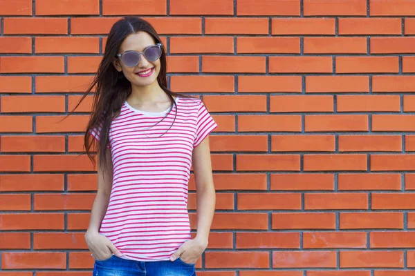 çekici genç kadın giyinmiş bir kırmızı ve beyaz çizgili kırmızı tuğladan bir duvar bir arka plan üzerinde poz t-shirt