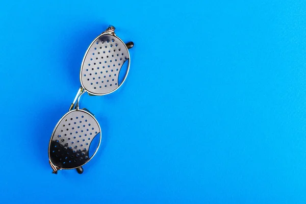 안경 트레이너입니다. 파란색 바탕에 블랙 핀 홀 안경입니다. 의료 개념입니다. 상위 뷰. — 스톡 사진
