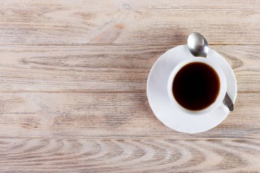 Fotokopi alanı olan ahşap arka plandaki kahve fincanının üst görüntüsü.