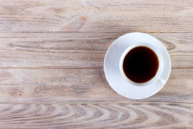 Bir fincan kahve, ahşap masa, üst manzara.