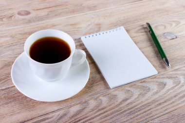 Boş not defteri ve kahve fincanı ofis tahtasının üzerinde.