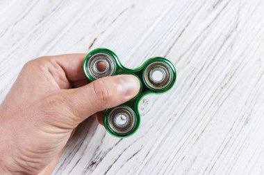 Çocuk el topluca spinner gadget ile oynuyor. Adam elinde dönen el oyuncak Kıpırdanmayı yeşil el getiriyor