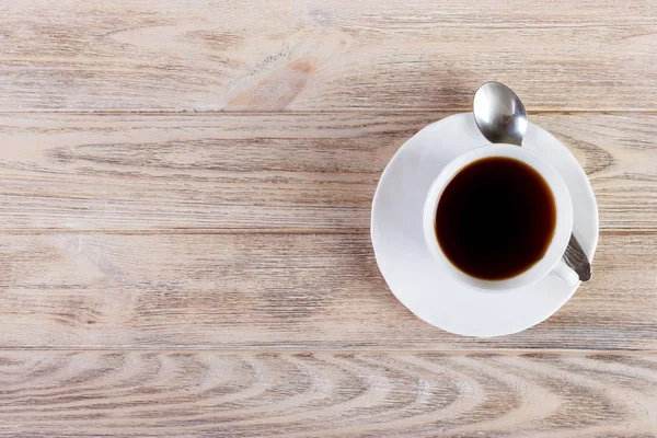 Fotokopi alanı olan ahşap arka plandaki kahve fincanının üst görüntüsü.