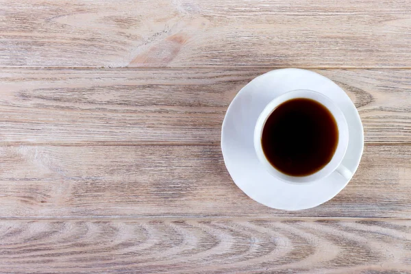 Bir fincan kahve, ahşap masa, üst manzara.