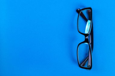 Mavi arka plan, mükemmel yansıma, gözlükleri kopya alanı masanın üzerine modern şık ve office gözlük