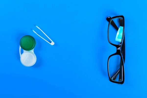 Kontaktlinser set med plastlåda och pincett med glasögon på bakgrunden planen på en lila bakgrund. Lagra och använda kontaktlinser — Stockfoto