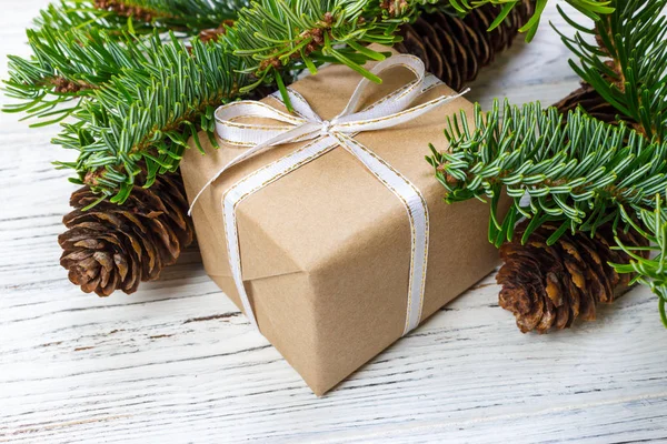 Caixa de presente de Natal no fundo da mesa de madeira branca, ramo de abeto, cones de pinho, quadro, vista superior, espaço para texto — Fotografia de Stock