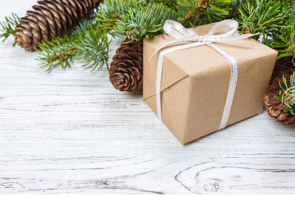 Çam kozalakları ve çam dalları ile karanlık rustik ahşap masa üzerinde Noel hediyeleri sarılmış. Metniniz için kopya alanı ile