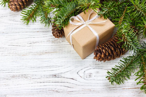 Caixa de presente de Natal no fundo da mesa de madeira branca, ramo de abeto, cones de pinho, quadro, vista superior, espaço para texto — Fotografia de Stock