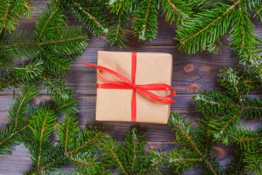 Çam dalları köpekler ile yapılmış bir çerçeve içinde koyu ahşap arka plan üzerinde kırmızı kurdele ile Noel hediyeleri. Düz yatıyordu stili