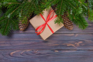 Noel ağacı dalı, süslemeleri ve hediye kutusu beyaz ahşap masa üzerinde