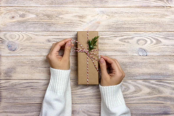 Woman holding a christmas gift in hand on wooden background — Stock Photo, Image