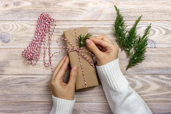 Женщина упаковывает подарки на Рождество. Руки женщины украшают рождественскую подарочную коробку — стоковое фото