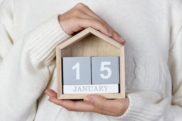 15 de enero en el calendario. la chica sostiene un calendario de madera. Día Mundial de la Nieve, Día Mundial de la Religión — Foto de Stock