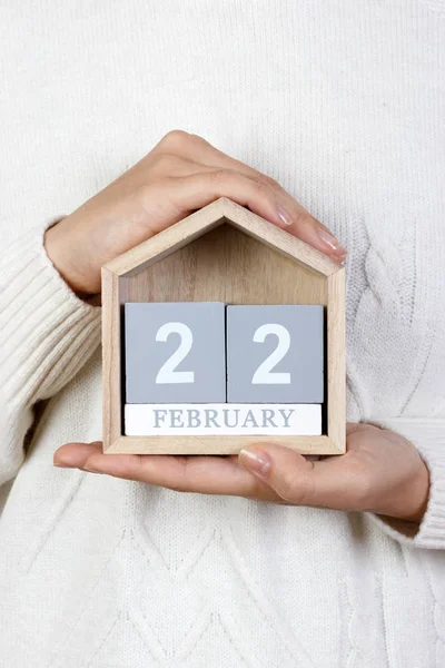 February 22 in the calendar. the girl is holding a wooden calendar. George Washington day, International Day of Support of Victims of Crime