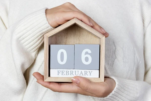 February 06 in the calendar. the girl is holding a wooden calendar. International Bartender's Day