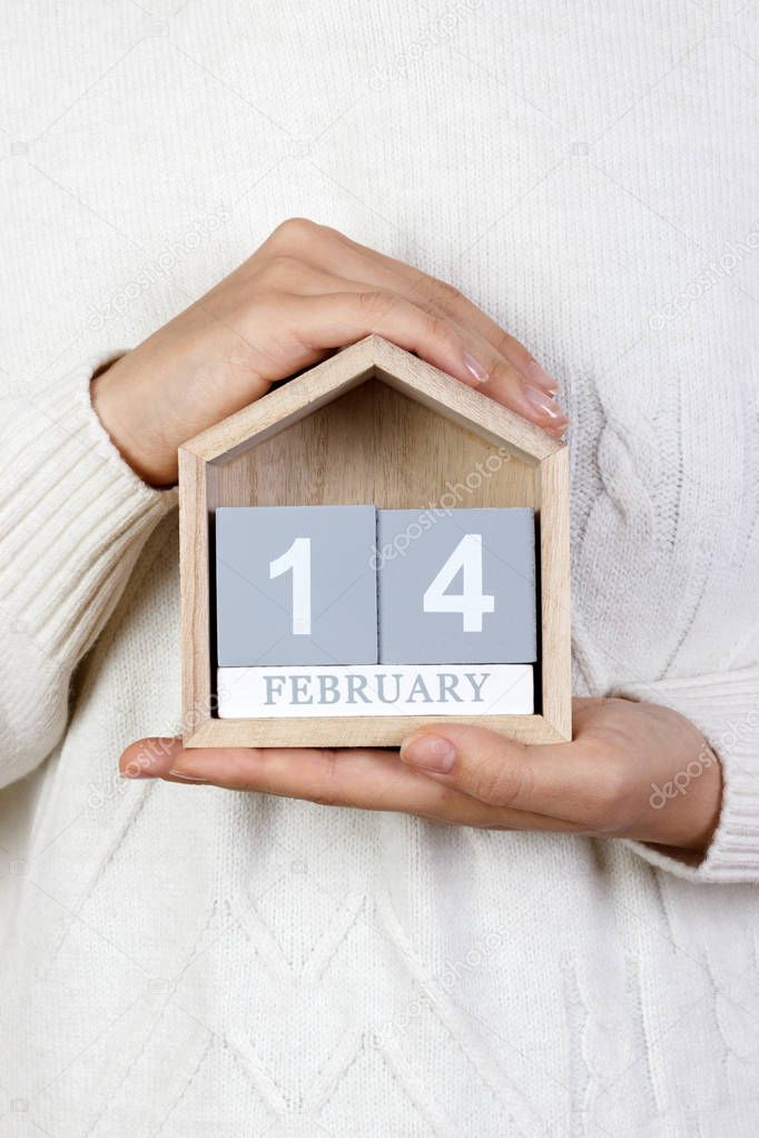 February 14 in the calendar. the girl is holding a wooden calendar. Valentine's Day, The International Day of Gift of Books, Day of the programmer